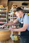 a man in an apron working on a cheese wheel