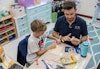 a man and boy sitting at a table with craft supplies