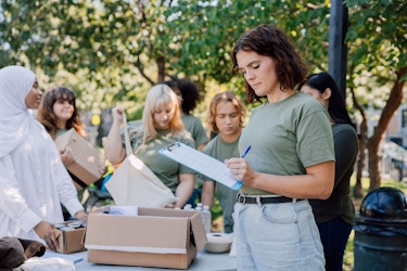  A woman holding a clipboard uses a pen to mark something on her checklist. 