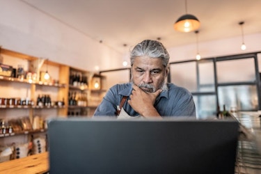 A worried store owner looks at information on his laptop computer.
