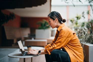 Woman business owner sitting with a coffee and working on her laptop.