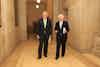 two men in suits walking in a hallway